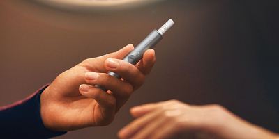 يدان تفتحان علبة جهاز IQOS.